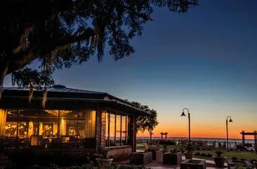 Twilight hues over a seaside restaurant with indoor lighting casting a warm glow.