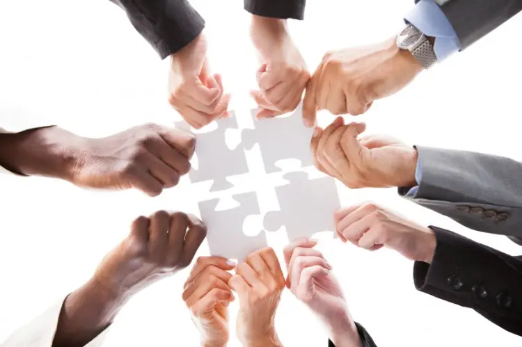 A group of people holding up puzzle pieces.