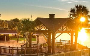 Sunset over lakeside wooden pavilion with palms