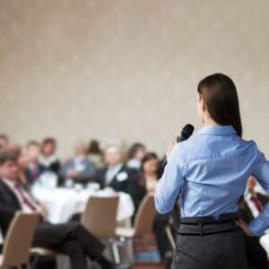 Woman presenter with microphone addressing audience