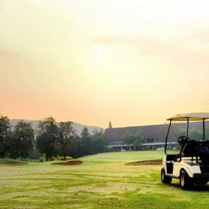 Golf cart on sunrise fairway near clubhouse