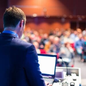 Speaker presenting with laptop to conference audience