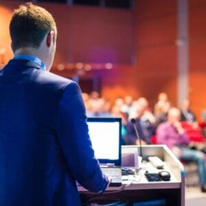 Conference presenter at podium with laptop